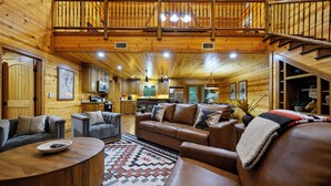 A log cabin interior with a living room, kitchen, and a balcony.