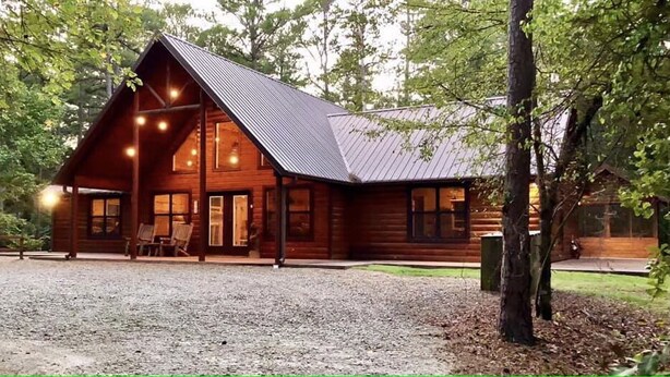 Une cabane en bois avec un toit en pente, de grandes fenêtres et une allée gravillonnée.