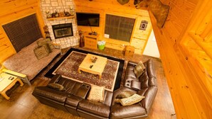 Un interior acogedor de cabaña de madera con chimenea, sofás de cuero y monturas de animales en las paredes.