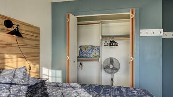 Une chambre à coucher comprenant un lit, une armoire, un ventilateur et une lampe fixée au mur.