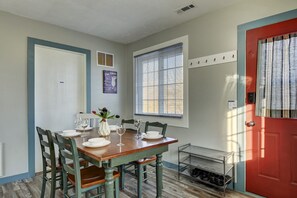A dining area with a table set for meals, featuring a vase with flowers and a coat rack.