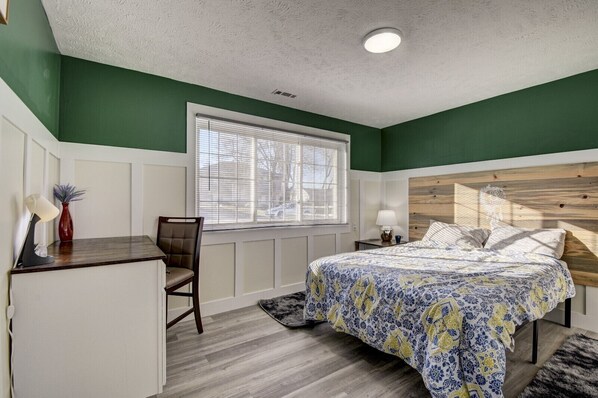 Un dormitorio con cama, escritorio y silla.
