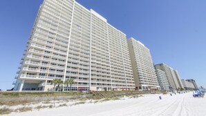 A high-rise hotel with multiple floors, balconies, and a beach view.