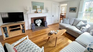 A living room with a fireplace, a television, and striped sofas. - Cozy Chatham home with privacy and nautical decor (Chatham)