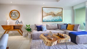 Una sala de estar moderna con un sofá modular, una mesa de centro de madera y un cuadro abstracto de gran tamaño en la pared.