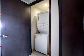 Een praktische wasruimte met een wasmachine, droger, een deur en een klein raam.