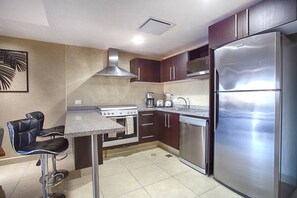 Una cocina moderna con refrigerador de acero inoxidable, microondas integrado, estufa y cafetera.