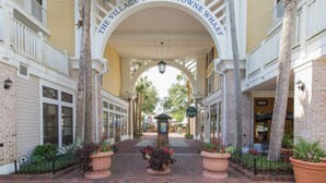 A brick pathway leading to a building with a sign reading "The Village of Baytowne Wharf".