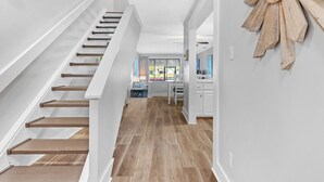 A modern interior with a wooden staircase, a kitchen area, and a dining space.
