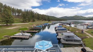 Ein Yachthafen mit Booten, die an einem ruhigen Wasserweg liegen, umgeben von bewaldetem Gebiet und Hügeln im Hintergrund.