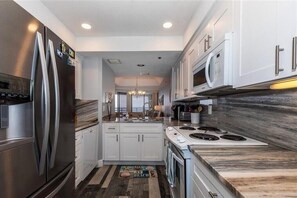 Enjoy cooking in this well-equipped kitchen with a refrigerator, microwave, and white cabinetry.