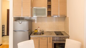 Une cuisine moderne avec des meubles en bois, un réfrigérateur en acier inoxydable, un four à micro-ondes, un évier et une cuisinière.