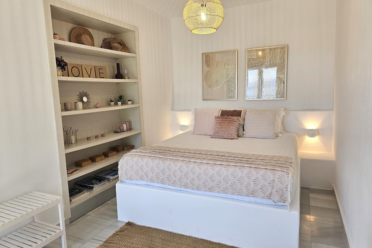 A bedroom with a bed, a white wardrobe, and two wall-mounted lights.