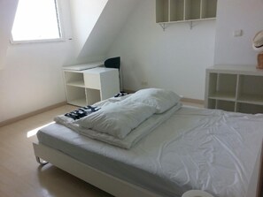 Quarto com uma cama, uma escrivaninha e uma estante.