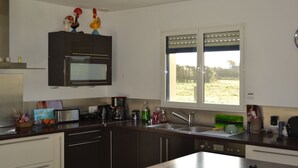Eine moderne Küche mit dunklen Schränken, einem Edelstahl-Kühlschrank und einem Fenster mit Blick ins Freie.