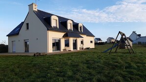 Ein modernes Haus mit geneigtem Dach, großen Fenstern und einem sichtbaren Schornstein.