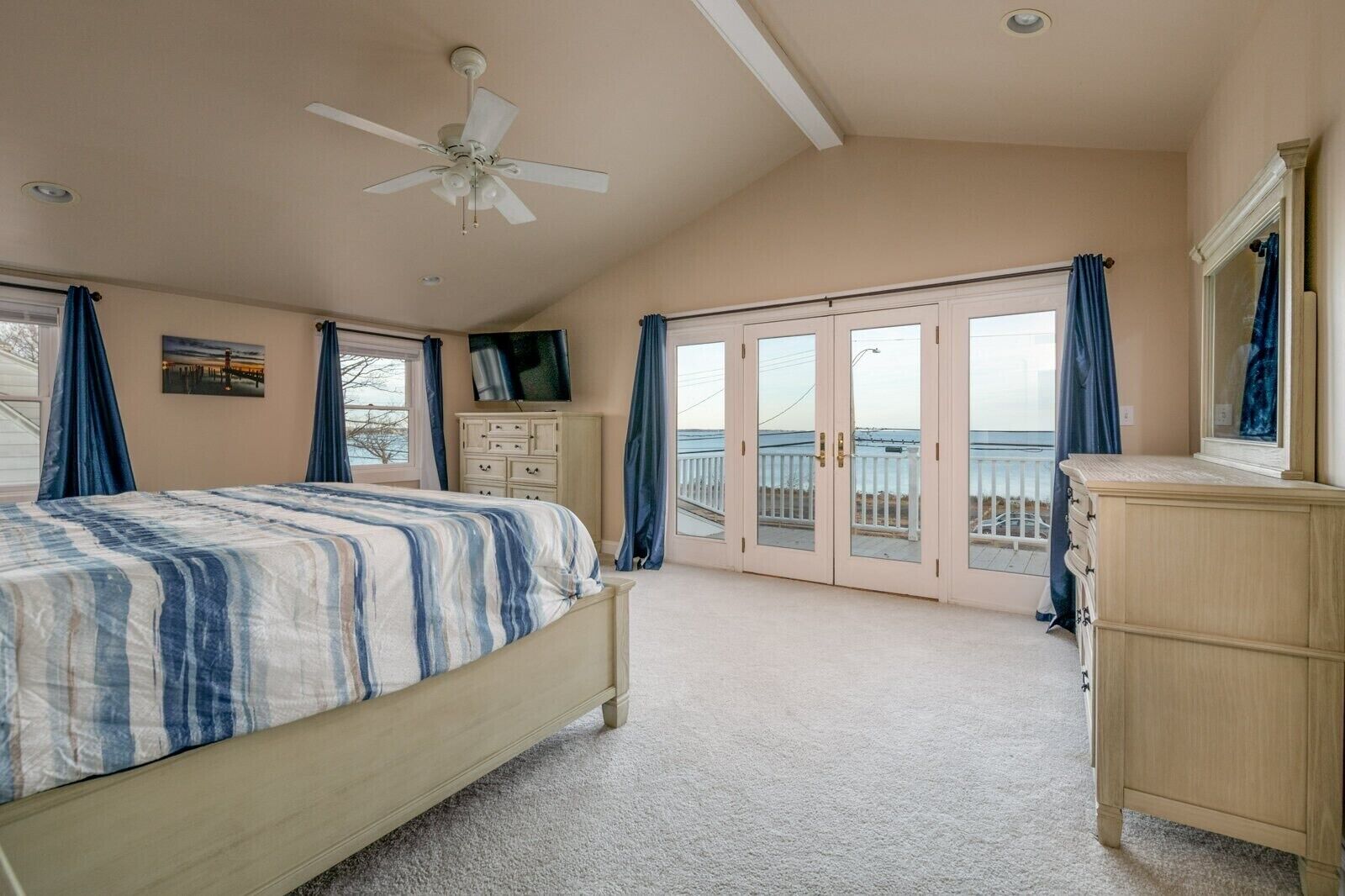 Une chambre avec un lit, une commode, une télévision et un balcon offrant une vue.
