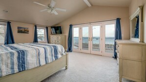 A bedroom with a bed, dresser, TV, and a balcony with a view. - Beautiful, Spacious, Beachfront Home - Perfect for Entertaining Family & Friends (West Haven)
