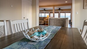 A dining area with a wooden table, white chairs, and a decorative centerpiece. - Beautiful, Spacious, Beachfront Home - Perfect for Entertaining Family & Friends (West Haven)