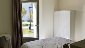 Un dormitorio con cama, escritorio y armario.