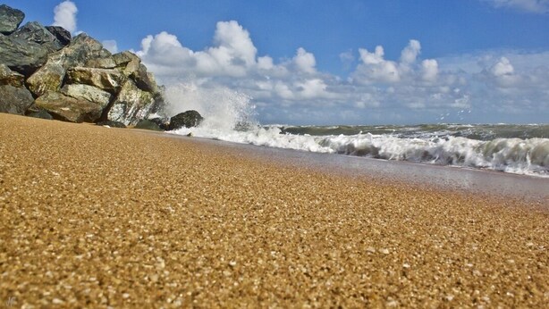 Una playa con arena pedregosa y rocas grandes.