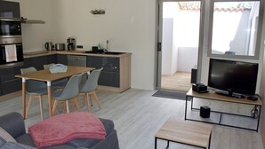 Un espacio habitable compacto con kitchenette, comedor, sofá y televisor.