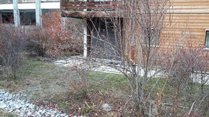 Un bâtiment doté d’une façade en bois, d’un espace extérieur couvert et d’un chemin de gravier.