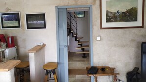 Een kamer met een trap, een lijst met een schilderij en een klein tafeltje met een stoel.