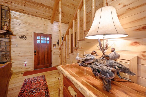 A wooden interior with a wooden door, a lamp, and decorative birds on a wooden table.