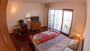 A bedroom with a bed, dresser, TV, and a balcony with a view. - Lux Panoramic Apartment (Budva)