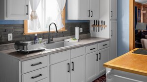 A modern kitchen with white cabinets, a stainless steel sink, and a wooden countertop. - Lakehouse at Pillar Point on Lake Ontario, a relaxing home with stunning sunsets (Dexter)