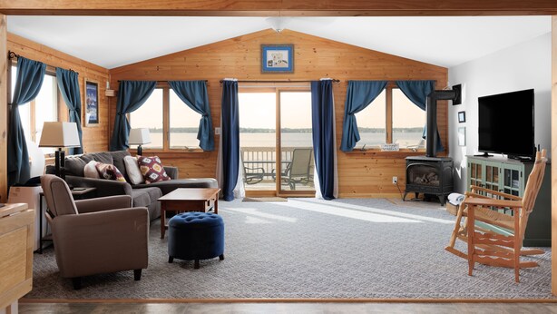 A cozy living room with a fireplace, a television, and a view of the lake. - Lakehouse at Pillar Point on Lake Ontario, a relaxing home with stunning sunsets (Dexter)