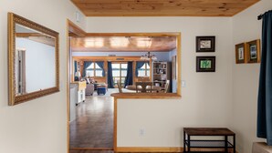 A wooden-framed mirror, a small table, and a view into a dining area with a sign reading "LIFE HOUSE". - Lakehouse at Pillar Point on Lake Ontario, a relaxing home with stunning sunsets (Dexter)