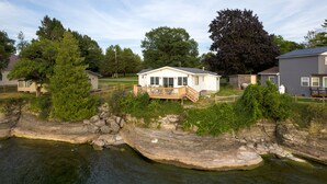 A lakeside cabin with a deck and a small shed. - Lakehouse at Pillar Point on Lake Ontario, a relaxing home with stunning sunsets (Dexter)