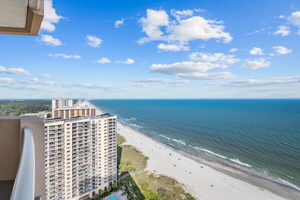 Un edificio alto con vistas a una playa, bajo un cielo despejado.