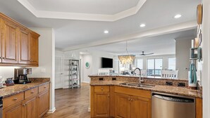 A spacious kitchen with wooden cabinets, granite countertops, and a stainless steel dishwasher. - 2507 Margate - 4 bedroom ocean front condo - (Myrtle Beach)
