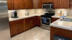 A kitchen with wooden cabinets, a stainless steel refrigerator, a microwave, a toaster, a stove, and a sink. - Bullhead City 3 Bedroom! Private Launch, & Beach! (Bullhead City)