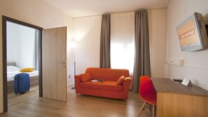 Een hotelkamer met een bed, een rode bank, een bureau en een televisie aan de muur.