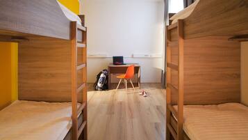 Une chambre de dortoir avec des lits superposés, un bureau, une chaise et un sac à dos.