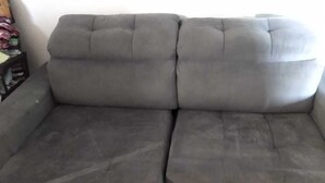 Un sofá seccional gris con respaldo y reposabrazos acolchados.