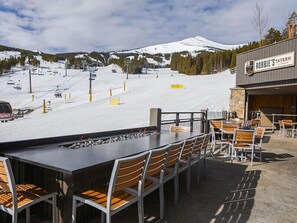 An outdoor seating area with a view of a ski slope and a mountain in the background.