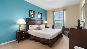 A bedroom with a large bed, two bedside tables with lamps, a chair, and a window with blinds. - Windsor Hills Resort Condo-Disney, Golf, and Fun! (Kissimmee)