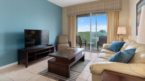 A living room with a TV, sofa, and a balcony with a view. - Windsor Hills Resort Condo-Disney, Golf, and Fun! (Kissimmee)