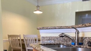 A kitchen with granite countertops, a stainless steel sink, and two wooden chairs. - Orlando Oasis II - Pool Open! Clean Spacious Villa By Disney (Kissimmee)
