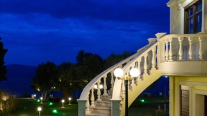 A grand staircase leading to a building with a balcony, surrounded by a well-lit garden path and decorative lighting. - Villa Filoxenia - by the sea - up to 12 guests (Aigialeia)