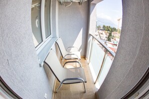 Un balcon étroit d’où l’on aperçoit un chantier de construction et des bâtiments au loin.