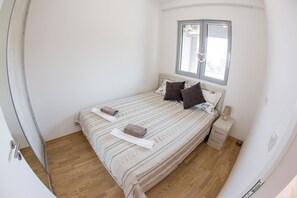 Une chambre à coucher avec un lit, une table de chevet, une fenêtre et une porte.