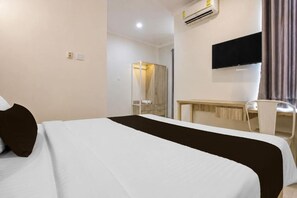 A hotel room with a bed, a desk, a chair, a TV, and an air conditioning unit. - Collection O Near Ambarrukmo Plaza Mall Formerly Damar Kusumo Guest House (Depok)