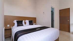 Une chambre d’hôtel avec un grand lit, une tête de lit en bois, une table de chevet et une armoire.