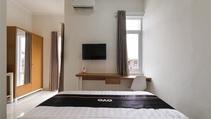 Une chambre d’hôtel équipée d’un lit, d’un bureau, d’une télévision et d’un climatiseur.